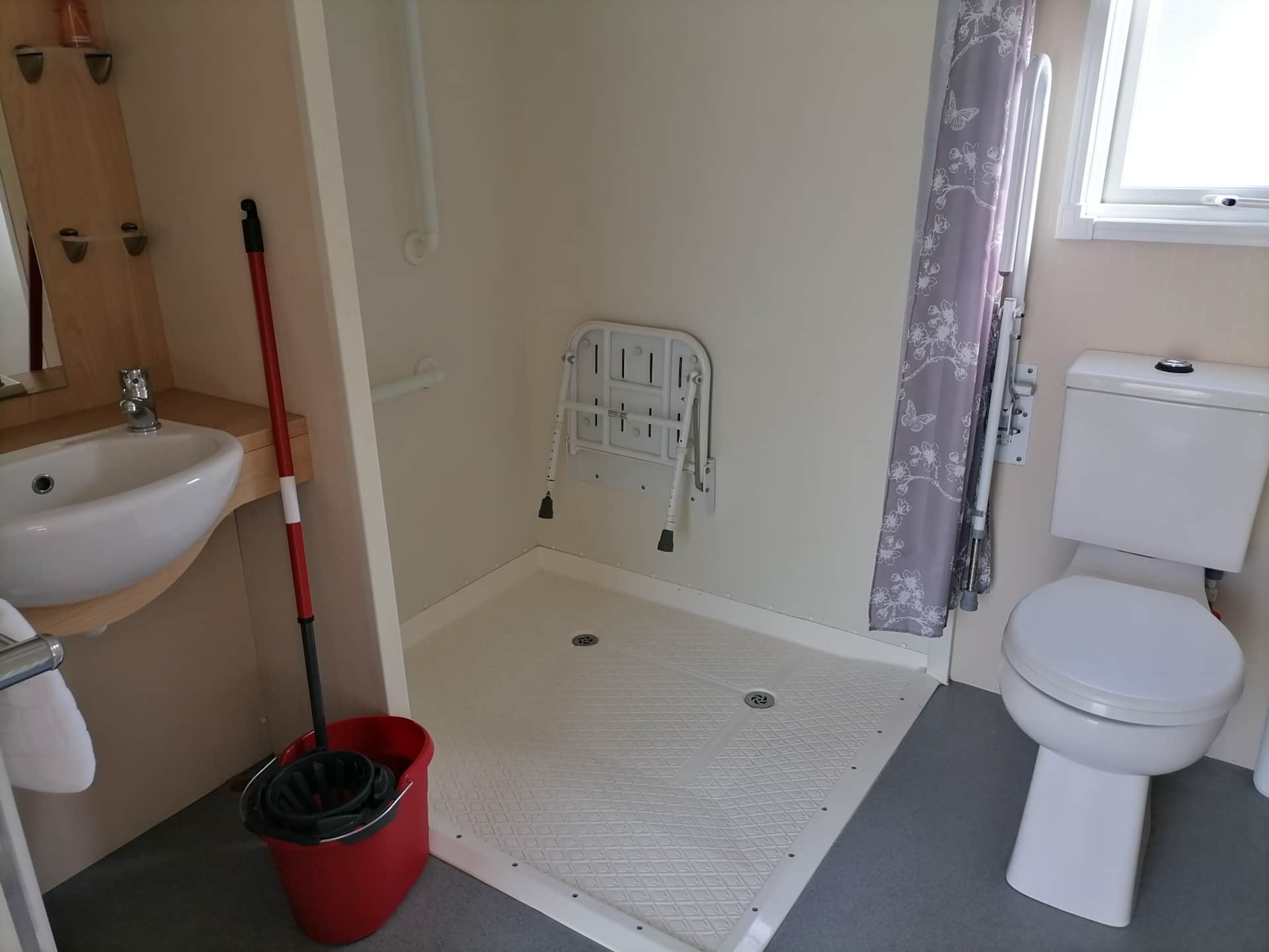 A bathroom with a shower seat and toilet.